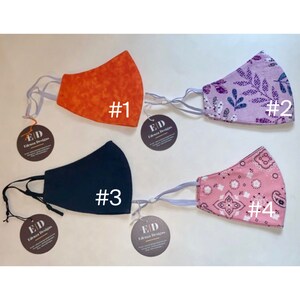 May include: Four different fabric face masks with various patterns. The masks are numbered 1 through 4. The masks are all made of cotton fabric and have elastic ear loops. The masks are all in a white background.