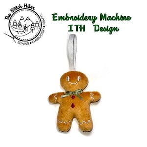 May include: A plush gingerbread man ornament with a smiling face, green bow, and red buttons. The ornament has a white ribbon for hanging and is labeled "Embroidery Machine ITH Design."
