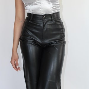 May include: A silver satin strapless corset top with a sweetheart neckline. The top is paired with black leather pants.