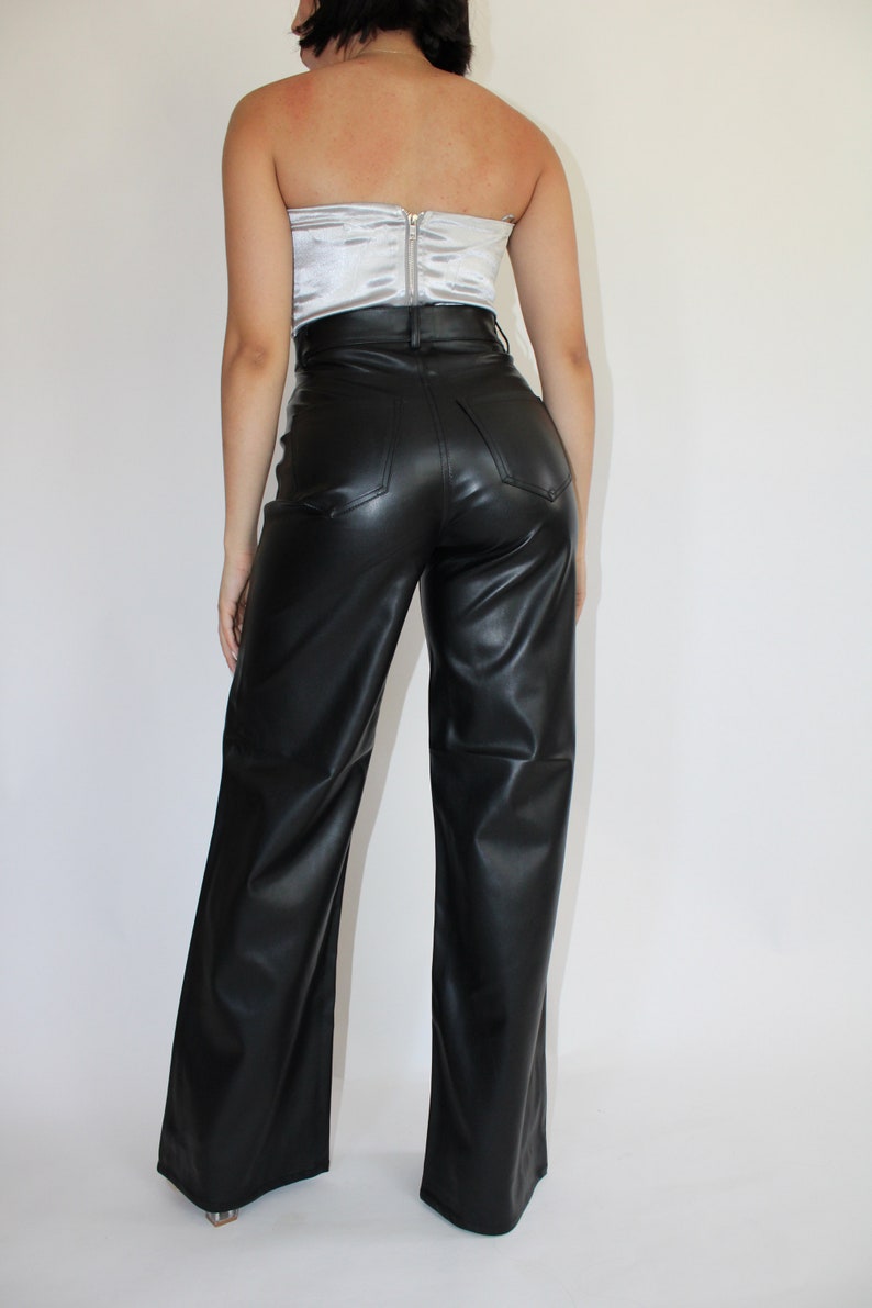 May include: Black faux leather wide-leg pants with a high waist and a zipper closure in the back.