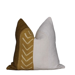 May include: A decorative pillow with a white and mustard yellow fabric. The mustard yellow side features a geometric pattern of white chevron shapes.