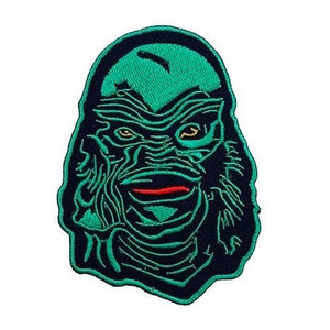 Op de afbeelding: Groen en zwart geborduurd pleister met het gezicht van het monster uit de Zwarte Lagune.