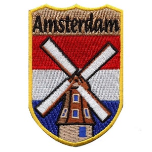 May include: An embroidered patch with a yellow border, featuring a windmill with the Dutch flag colors of red, white, and blue. The text "Amsterdam" is displayed at the top of the patch.