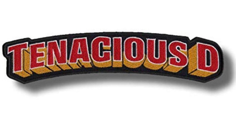 Pode incluir: Um remendo bordado preto e dourado com o texto "Tenacious D" em letras vermelhas.