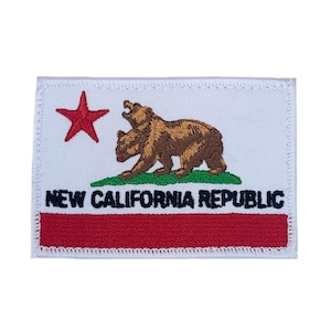 May include: White embroidered patch with a red star, a brown bear, and green grass. The text "NEW CALIFORNIA REPUBLIC" is in black letters.