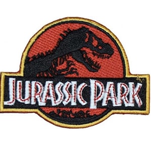 Może przedstawiać: Naszywka haftowana w kolorze czerwonym, żółtym i czarnym z logo Jurassic Park. Logo przedstawia sylwetkę dinozaura i napis "Jurassic Park" w kolorze białym z czerwonymi ściegami.