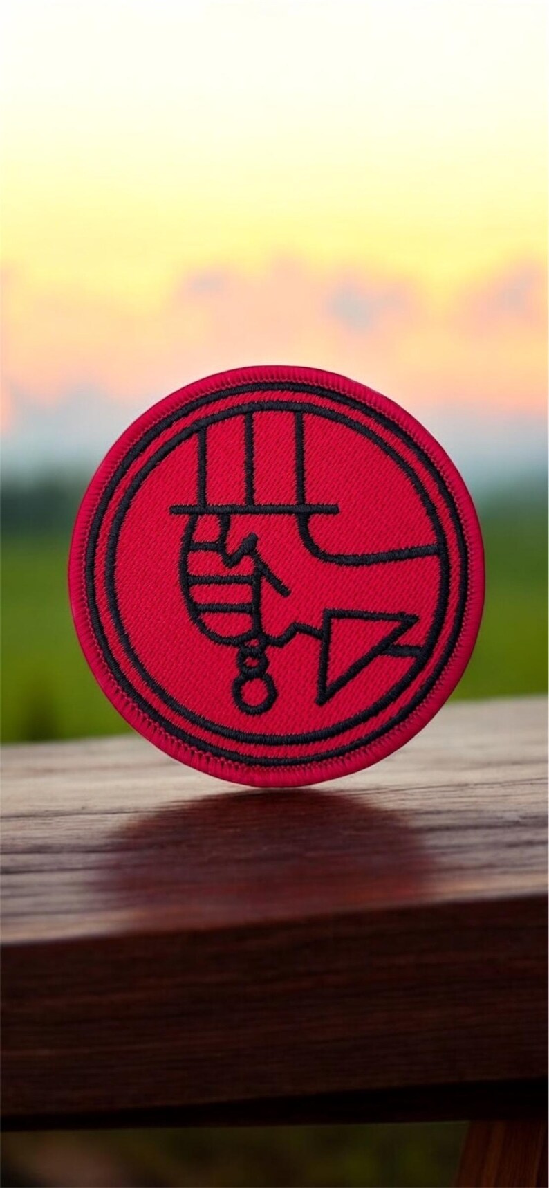 May include: A red embroidered patch with a black outline. The patch features a stylized image of a hand holding a knife.