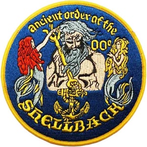 May include: A blue and yellow embroidered patch with the text "Ancient Order of the Shellbacks" and a depiction of a bearded man holding a trident, flanked by two mermaids.