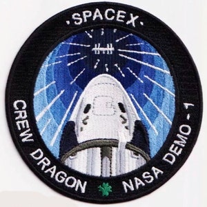 May include: A black and white embroidered patch with a white spaceship against a blue background. The patch reads "SpaceX Crew Dragon NASA Demo-1".