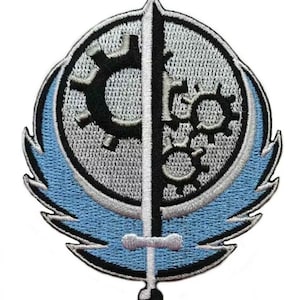 Może przedstawiać: Haftowana naszywka z okrągłym wzorem, przedstawiająca czarną zębatkę i miecz dzielący okrąg. Naszywka ma po bokach jasnoniebieskie kształty przypominające skrzydła, obramowane na czarno i biało. Do odzieży lub akcesoriów.