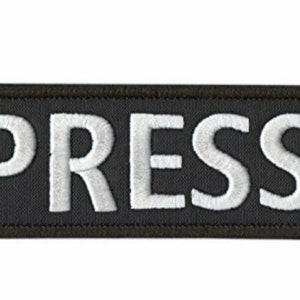Peut inclure: Écusson rectangulaire noir avec du texte brodé en blanc qui dit "PRESS".