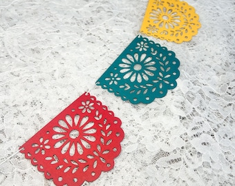 May include: A decorative garland featuring a series of semi-circular paper cutouts in red, yellow, and teal. Each piece displays an intricate, symmetrical floral pattern with scalloped edges, all strung together on a thin white cord.