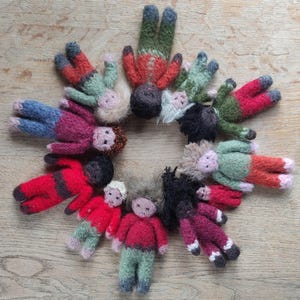 May include: A circle of knitted dolls in various colors and patterns, including red, green, blue, and brown. The dolls are arranged in a circle, with their heads facing inward.