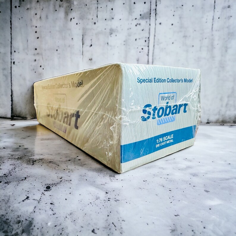Op de afbeelding: Een gele kartonnen doos met een blauw en wit label. Het label zegt "Special Edition Collector's Model World of Stobart 1:76 Scale Die-Cast Metal".