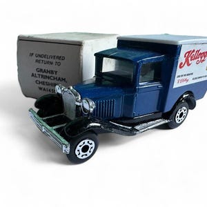 Op de afbeelding: Een blauwe Kellogg's bestelwagen speelgoed met een wit dak en zwarte wielen. De vrachtwagen heeft het Kellogg's logo op de zijkant en een doos erachter met tekst. Een klassiek verzamelobject.