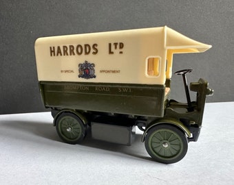 Puede incluir: Un camión de reparto de juguete verde con un techo blanco y las palabras "Harrods Ltd" impresas en el lateral. El camión tiene un escudo con las palabras "By Special Appointment" y "Brompton Road, S.W.I."