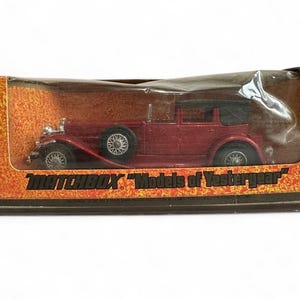 May include: A vintage Matchbox model car in its original box. The car is a burgundy color with a black convertible top and silver wheels. The box has an orange and brown design with the text "MATCHBOX 'Models of Yesteryear'".