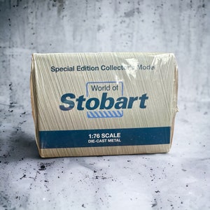 Op de afbeelding: Een kartonnen doos met een gele achtergrond en blauwe accenten. De doos heeft de tekst "Special Edition Collector's Model" en "World of Stobart" in een vet, wit lettertype. De doos bevat ook de tekst "1:76 Scale Die-Cast Metal".