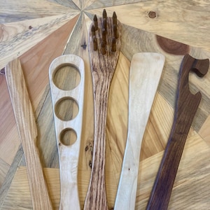 May include: Five wooden kitchen utensils, including a spatula, a slotted spoon, a spoon with three holes, a whisk, and a bottle opener. The utensils are made of different types of wood, including maple, walnut, and cherry.