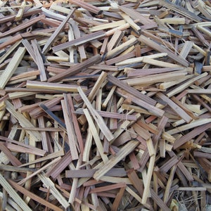 May include: A collection of split wooden pieces in shades of brown, tan, and grey. The rectangular pieces vary in length, creating a textured, natural appearance. The image suggests a rustic or natural theme, possibly for kindling or crafts.