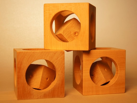 A hand-turned wooden rattle that hides a square-within-a-square geometric puzzle inside — sustainably sourced, triple-duty as toy, puzzle, and ornament.