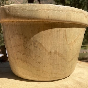 Peut inclure: Un grand bol en bois brun clair avec une surface lisse et arrondie. Le bol est fait de bois naturel et présente un motif de grain naturel clair.