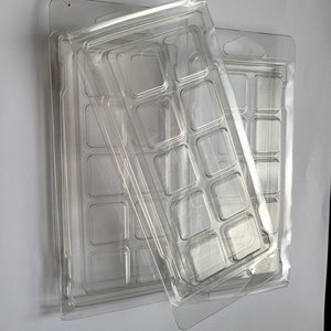 May include: Two clear plastic trays with multiple square compartments. The trays are stacked on top of each other.