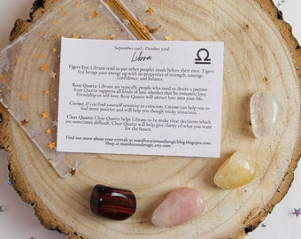 May include: A set of three crystals for Libra zodiac signs. The crystals are Tiger's Eye, Rose Quartz, and Citrine. The crystals are on a wooden surface with a white background. The text on the card reads: "September 23rd - October 23rd Libra Tigers Eye: Librans tend to put other people's needs before their own. Tigers Eye brings your energy up with its properties of strength, courage, confidence, and balance. Rose Quartz: Librans are typically people who need or desire a partner. Rose Quartz supports all kinds of love whether that be romantic love, friendship or self-love. Rose Quartz will attract love into your life. Citrine: If you find yourself sensitive to criticism, Citrine can help you to feel more positive and will help you through tricky situations. Clear Quartz: Clear Quartz helps Librans to be make clear decisions which are sometimes difficult. Clear Quartz will help give clarity of what you want for the future. Find out more about your crystals at manifestationandmagicblog.blogspot.com Shop at manifestandmagic.etsy.com"