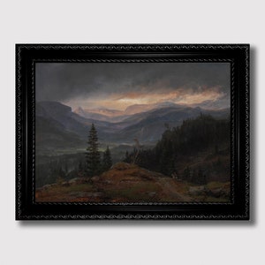 May include: A framed landscape painting depicts a mountain valley scene under a dramatic sky. The artwork features dark green trees, brown hills, and distant mountains. The sky transitions from dark grey to orange and yellow hues. The painting is enclosed in a black ornate frame.