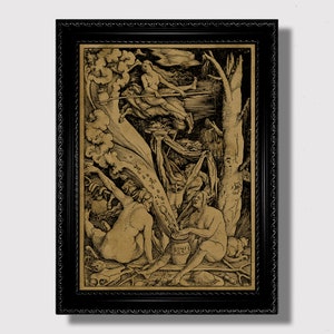 May include: A black and white woodcut print depicting a scene of witchcraft. The print features a woman riding a broomstick, a cauldron, and several figures in a forest setting. The print is framed in a black frame.