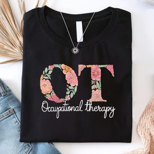May include: Black t-shirt with a floral design that spells out "OT" for Occupational Therapy.