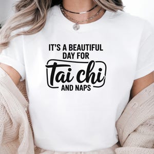 May include: White t-shirt with black text that reads "It's a beautiful day for Tai Chi and Naps".