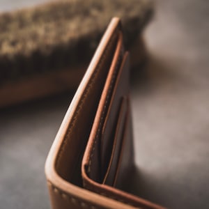 May include: A brown leather wallet with multiple compartments, folded open to reveal the interior.
