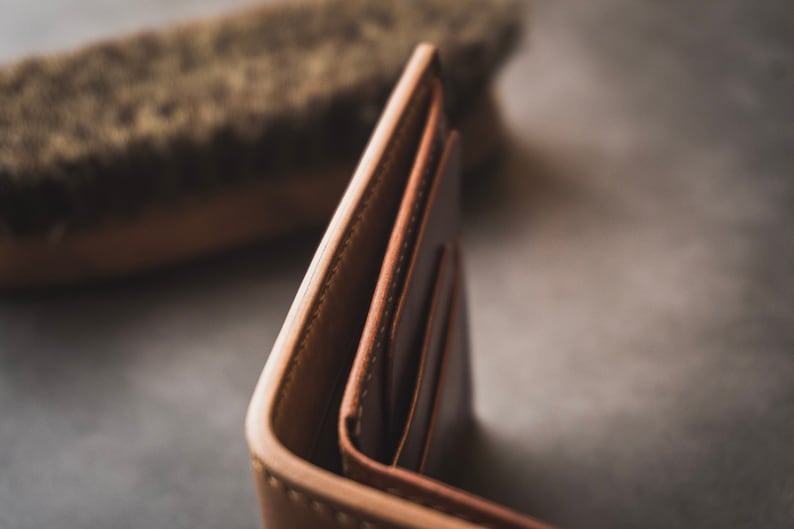 May include: A brown leather wallet with multiple compartments, folded open to reveal the interior.