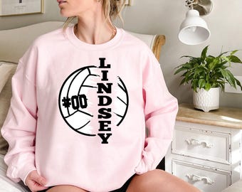 May include: Pink sweatshirt with a black volleyball graphic and the name Lindsey and the number 00.