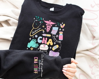 May include: Black sweatshirt with a colorful CNA graphic featuring medical symbols like a stethoscope, caduceus, and nurse's cap. The sleeve reads "CNA STUFF" and "Can't talk right now, Doing CNA stuff."