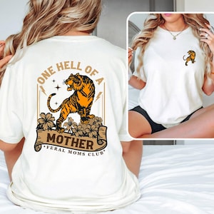 May include: White t-shirt with a tiger graphic and the text "One Hell of a Mother - Feral Moms Club".