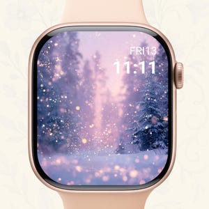 May include: A rose gold smartwatch displaying a winter forest scene with snow-covered trees and sparkling lights. The screen shows the date, Fri 13, and the time, 11:11, in white text. The watch has a light pink band.