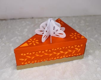 May include: Orange and white paper craft box shaped like a slice of pie with a white paper cutout of a flower on top.