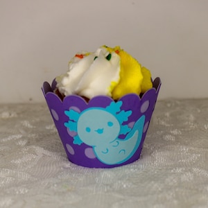 May include: Purple cupcake wrapper with a blue axolotl design and white frosting with yellow and rainbow sprinkles.