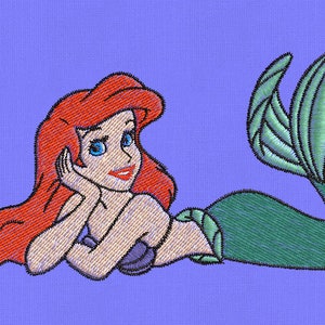 Pode incluir: Uma sereia de cabelo ruivo e olhos azuis, com uma cauda verde, está deitada sobre um fundo roxo. Ela está sorrindo e tem a mão no queixo.
