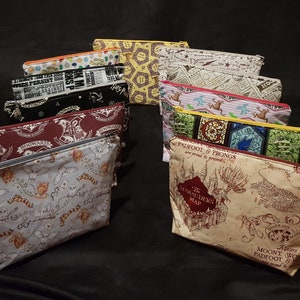May include: A collection of 10 Harry Potter themed zippered pouches. The pouches are made of fabric and feature various designs, including the Hogwarts crest, the Marauder's Map, and the quote "Padfoot & Prongs are proud to present".