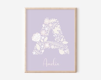 Puede incluir: Un diseño de arte de pared imprimible con una letra A floral blanca sobre un fondo morado claro. El nombre Amelia está escrito debajo de la letra.