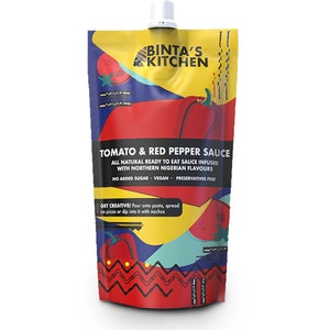 Op de afbeelding: Een rode en gele zak met een witte tuit, met het label "BINTA'S KITCHEN TOMATO & RED PEPPER SAUCE". De zak heeft een ontwerp met een rode peper en een tomaat. De tekst op de zak luidt "ALL NATURAL READY TO EAT SAUCE INFUSED WITH NORTHERN NIGERIAN FLAVOURS NO ADDED SUGAR - VEGAN - PRESERVATIVES FREE GET CREATIVE! Pour onto pasta, spread on pizza or dip into it with nachos".