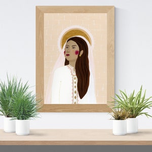 May include: A framed illustration of a woman with long brown hair wearing a white dress and a halo. The background is a light peach color with a brick pattern.