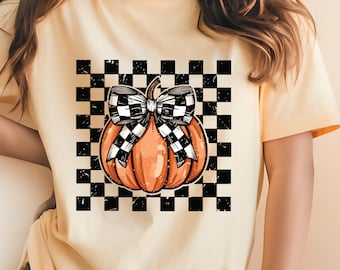 May include: A yellow t-shirt featuring a black and white checkered pattern with a pumpkin topped with a black and white checkered bow.