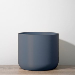 May include: A dark gray ceramic planter with a rounded bottom and a smooth, matte finish.