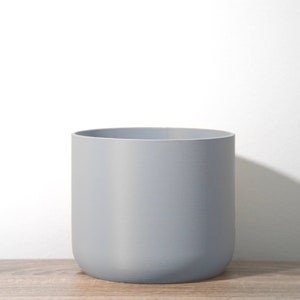 May include: A gray ceramic planter with a rounded bottom and a smooth, matte finish.