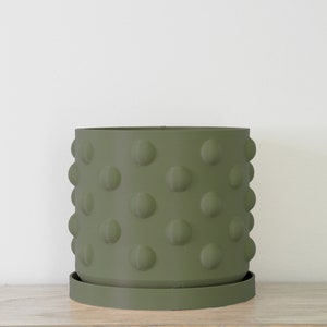 May include: A green ceramic planter with a textured, dotted surface. The planter has a matching saucer.