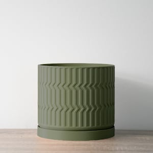 Pode incluir: Um vaso de cerâmica verde com um padrão geométrico. O vaso tem um pires correspondente.